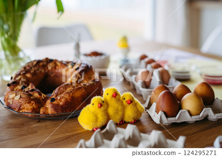 Traditional Easter table with dyed eggs, festive sweet bread and decorative chicks. 124295271