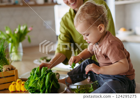 Mom and little boy preparing lettuce salad to celebrate Easter Green Thursday. Mom and little boy preparing lettuce salad to celebrate Easter Green Thursday. 124295275