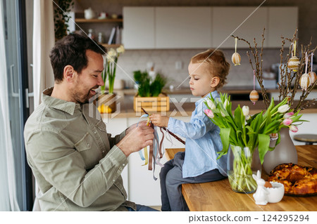 Father and little boy braiding easter whip from willow branches. Easter tradition concept. Father and little boy braiding easter whip from willow branches. Easter tradition concept. 124295294