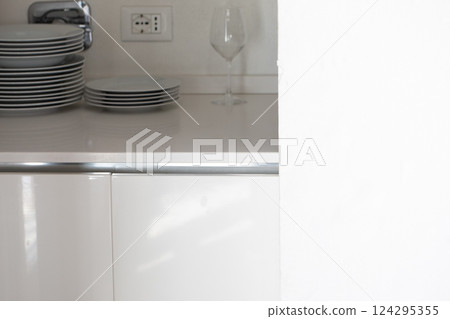 Plates and wine glass resting on modern kitchen counter 124295355