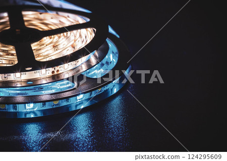 Colorful LED Strip Lights Spooling on Black Surface 124295609