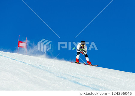 skier in whirlwind of snow down snow-covered slope during competitive downhill skiing 124296046