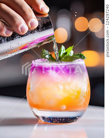 Bartender pouring colorful cocktail into glass with ice and mint 124297240