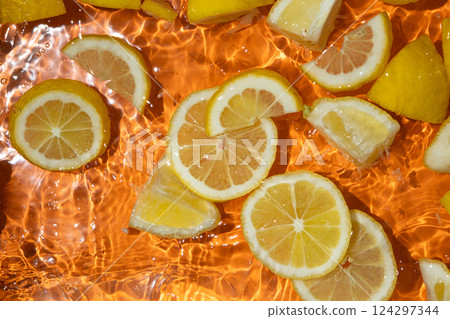 Slices of fresh lemons in water, splash of water, fresh orange background, top view 124297344
