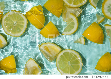 Refreshing turquoise citrus background with floating yellow lemon pieces 124297345