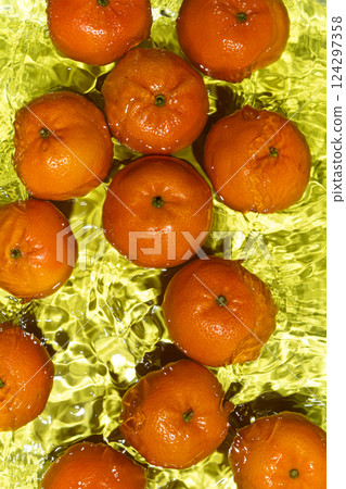 Tangerines in motion creating dynamic water ripples Tangerines in motion creating dynamic water ripples 124297358