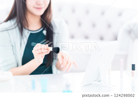 A young woman checking the color of powder with a makeup brush, no face 124298002