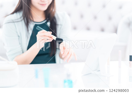 一位年輕女子用化妝刷檢查粉末的顏色，沒有臉 124298003