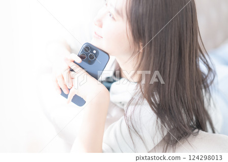 A young woman lying down and relaxing while looking at her smartphone 124298013