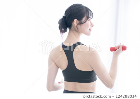 The back of a young woman doing slow training with weights 124298034