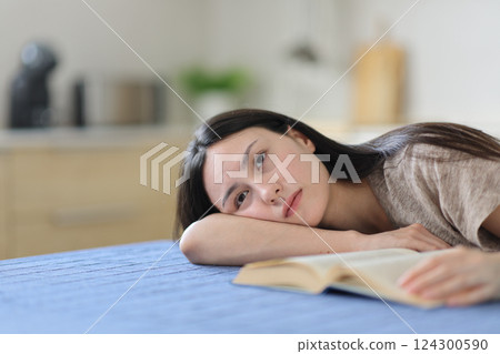 Asian apathetic woman with a book looking away 124300590