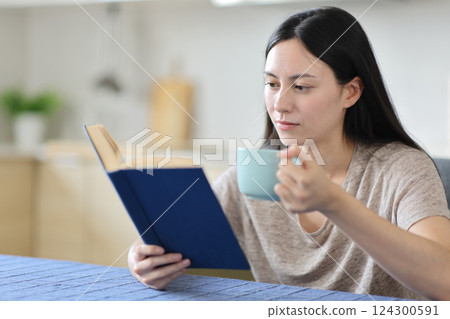 Asian woman at breakfast reading a paper book Asian woman at breakfast reading a paper book 124300591