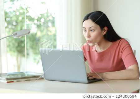 Amazed asian woman checking content on laptop Amazed asian woman checking content on laptop 124300594