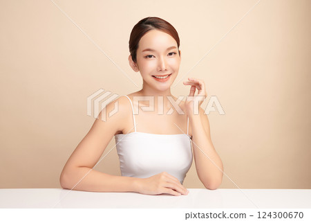 A beautiful young Asian woman with clean, fresh skin against a beige background. Skincare, facial treatment, cosmetology, beauty, and spa. An elegant portrait of an Asian woman. A beautiful young Asian woman with clean, fresh skin against a beige background. Skincare, facial treatment, cosmetology, beauty, and spa. An elegant portrait of an Asian woman. 124300670