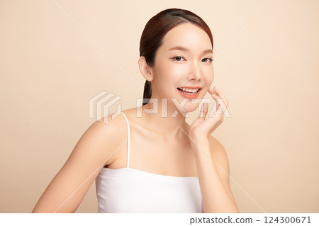 A beautiful young Asian woman with clean, fresh skin against a beige background. Skincare, facial treatment, cosmetology, beauty, and spa. An elegant portrait of an Asian woman. 124300671
