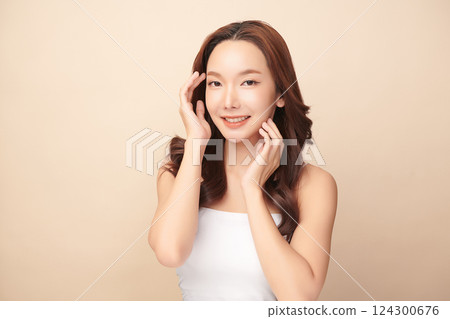 A beautiful young Asian woman with clean, fresh skin against a beige background. Skincare, facial treatment, cosmetology, beauty, and spa. An elegant portrait of an Asian woman. 124300676