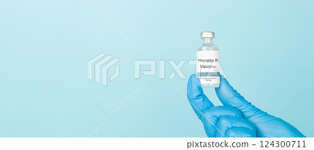 Doctor hand in blue gloves holding hepatitis B vaccine vial over blue background. Hepatitis B vaccine used to prevent hepatitis B virus infection, which can lead to cirrhosis and liver cancer. 124300711