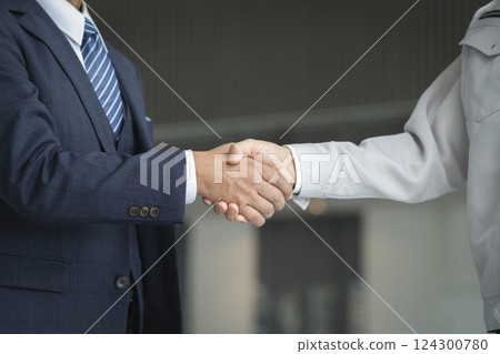 商業形象:一位穿西裝的商人和一位穿著工作服的男士握手 商業形象:一位穿西裝的商人和一位穿著工作服的男士握手 124300780