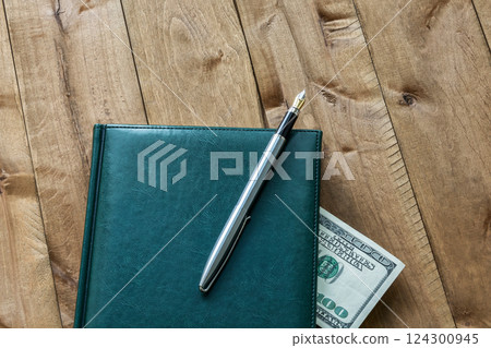 Diary, pen and part of a bill on a wooden surface 124300945