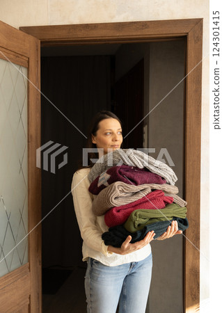 housewife holds stack of clothes or underwear in hands. washing shirts and sweaters. housework. 124301415