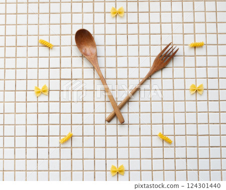 time to eat pasta. wooden plate with fork and spoon in form of clock hands. pasta on plate. time to eat pasta. wooden plate with fork and spoon in form of clock hands. pasta on plate. 124301440