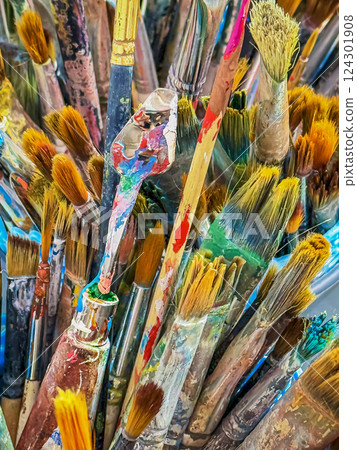 Colorful assortment of paintbrushes in an artist's studio during a creative session. Vibrant collection of various paintbrushes of artist. Brushes are dipped in colorful paints, creativity concept 124301908