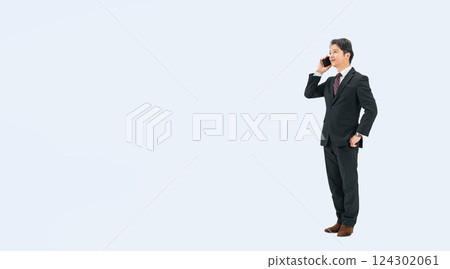 Full-body photo of a middle-aged male business person talking on a smartphone 124302061