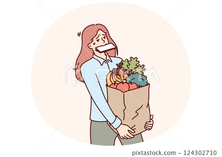 Woman carries shopping bag and holds phone in mouth after returning from market with organic food 124302710
