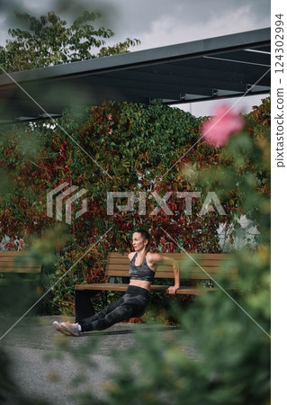Woman performing a stretching exercise in a park surrounded by colorful autumn foliage 124302994