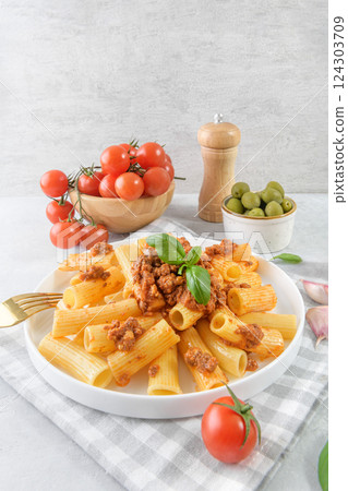 Rigatoni pasta dish with Bolognese sauce and fresh basil leaves, grand angle view 124303709