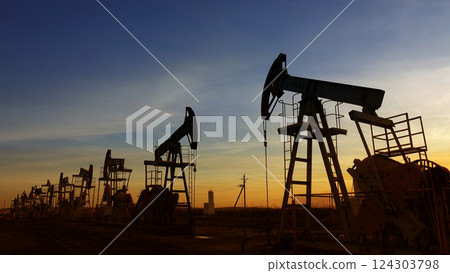 many working oil pumps silhouette against sunset 124303798
