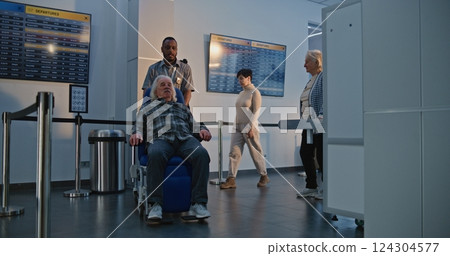 Airport Terminal: Senior Man Getting Up from Wheelchair, Walking Through Metal Detector Scanning Gates Airport Terminal: Senior Man Getting Up from Wheelchair, Walking Through Metal Detector Scanning Gates 124304577