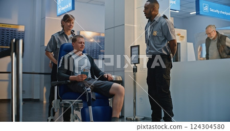 TSA Officer Checking Man with Bionic Prosthetic Leg in Wheelchair in Airport Terminal TSA Officer Checking Man with Bionic Prosthetic Leg in Wheelchair in Airport Terminal 124304580