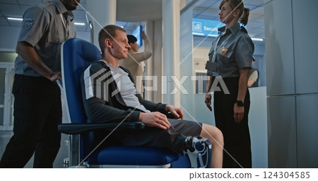 Airport: Man with Prosthetic Leg Getting Up from Wheelchair, Passing X-ray Metal Detector Scanner 124304585