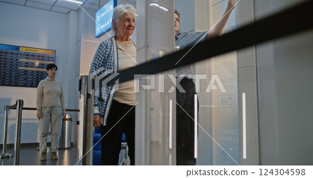 Senior Woman Getting Up from Wheelchair, Passing X-ray Metal Detector Scanner in Airport Terminal Senior Woman Getting Up from Wheelchair, Passing X-ray Metal Detector Scanner in Airport Terminal 124304598