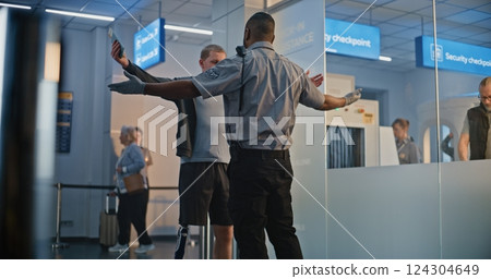 TSA Officer Checking Young Man with Prosthetic Leg in Airport Terminal 124304649