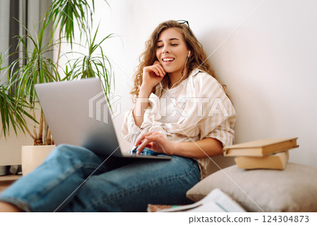 Young woman sits at home, learning preparing for exam using literature laptop, concept of knowledge. 124304873