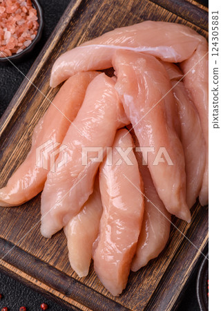 Raw chicken fillet cut into strips with spices and herbs Raw chicken fillet cut into strips with spices and herbs 124305881