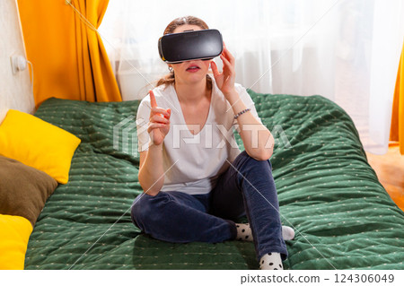 Female relaxing in a modern bedroom, enjoying innovative VR content. Top view 124306049