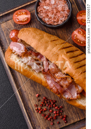 Delicious juicy hot dog with sausage, bacon, sauce, salt and spices Delicious juicy hot dog with sausage, bacon, sauce, salt and spices 124306657