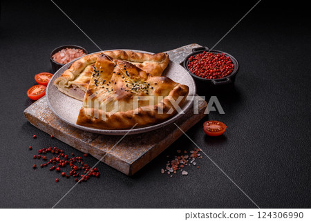 Cheburek meat pastry pie with herbs on the concrete background Cheburek meat pastry pie with herbs on the concrete background 124306990