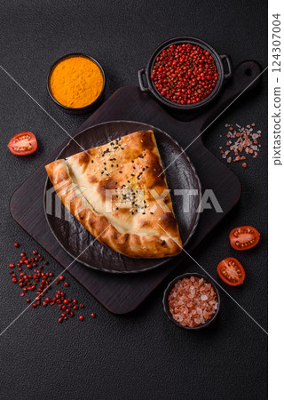 Cheburek meat pastry pie with herbs on the concrete background Cheburek meat pastry pie with herbs on the concrete background 124307004