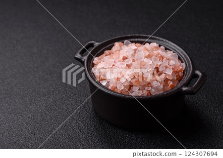 Pink himalayan salt in a black bowl on a dark concrete background 124307694