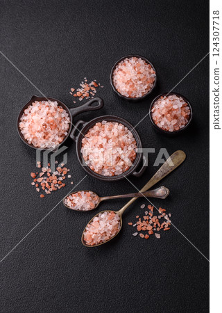 Pink himalayan salt in a black bowl on a dark concrete background 124307718