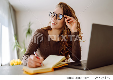 Business woman in casual clothes works with a laptop and notepad. Concept of education, freelancing. 124308179
