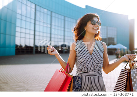 Shopping time. Young woman with shopping bags near the mall. Consumerism, sale, purchases. 124308771