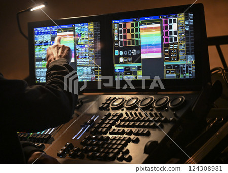 Lighting technician controls stage setup during evening concert in a vibrant venue with dynamic 124308981
