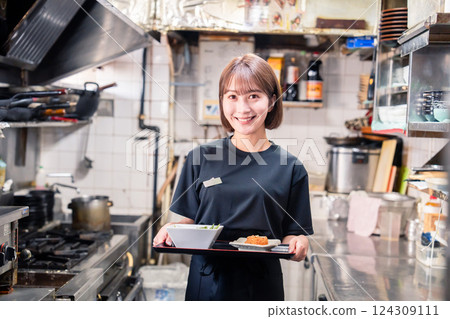 A young female staff member working in a restaurant kitchen A young female staff member working in a restaurant kitchen 124309111