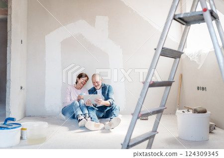 Senior couple renovating their home, browsing for inspirations on tablet. 124309345