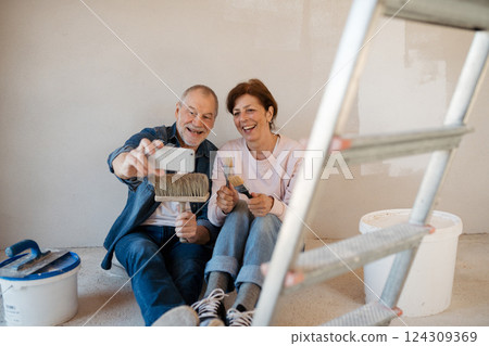 Senior couple taking break during their home renovation, taking a selfie. 124309369